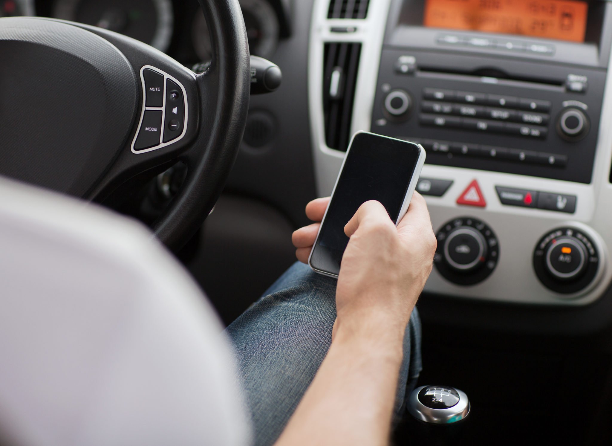 Driver using smartphone image via Shutterstock.