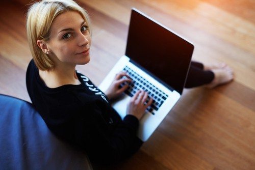A woman on a laptop looking over her shoulder at the camera.