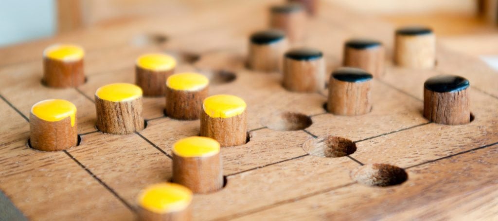 A game board with yellow and black pieces.