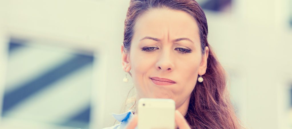 A woman looking skeptically at her phone.