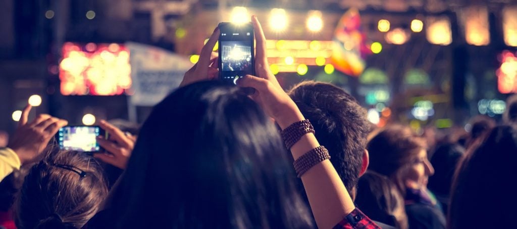 Music festival-goers taking video at a concert