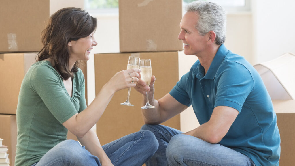 A couple sharing a champagne toast on the floor in their new house
