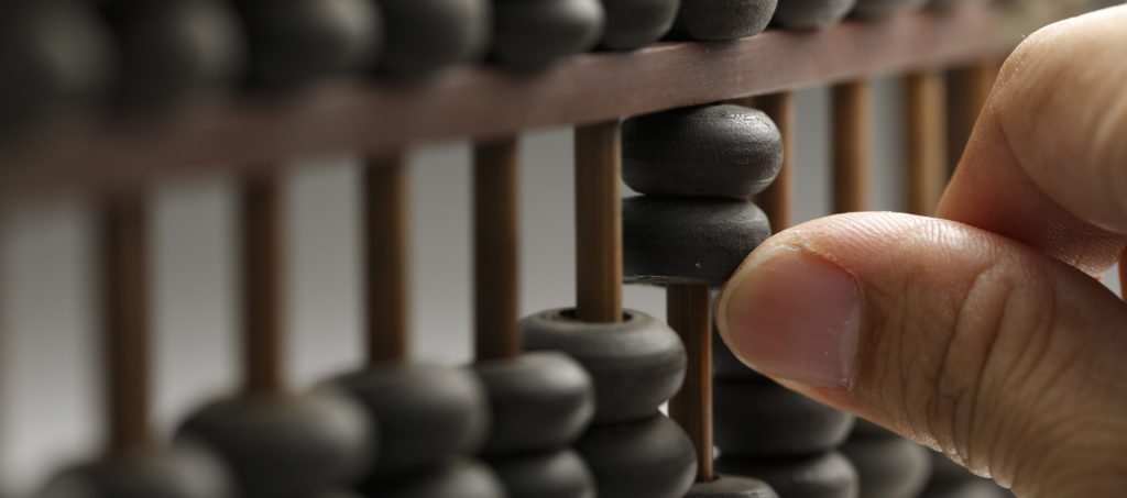 A hand moving beads on an abacus