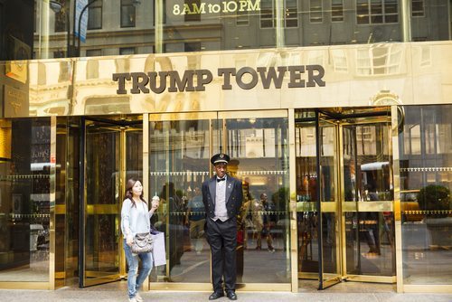 A doorman stands at the entrance to Trump Tower on Fifth Avenue in New York City. People can be seen going in and out of the doors of this luxury residence | DW labs Incorporated / Shutterstock.com