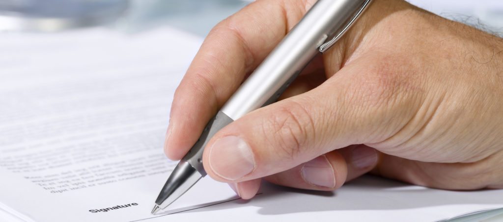 A hand signing a document