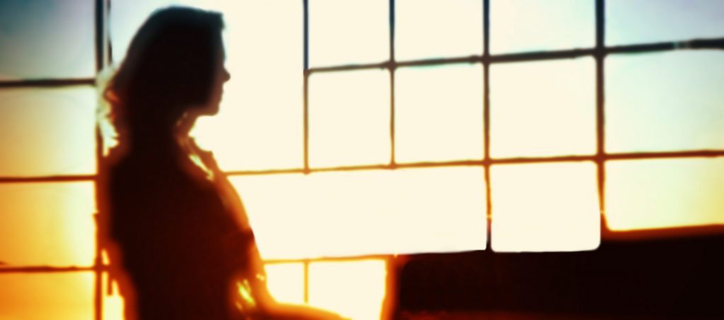 A woman working in a office, backlit by a window