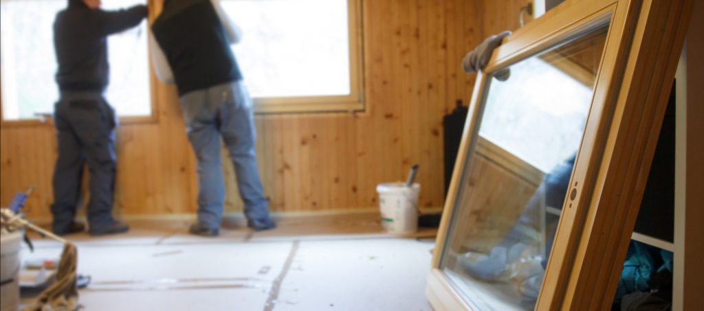 Two men installing a window in a house