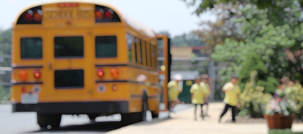 Kids getting off a school bus in blurred focus