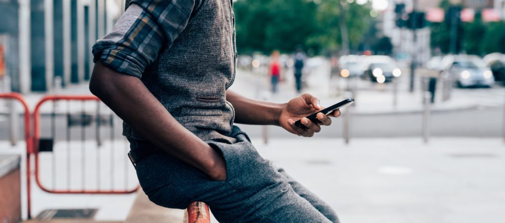 A millennial black man using a cell phone