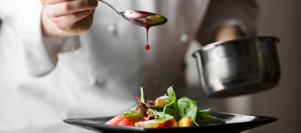 A chef drizzling sauce on a dish