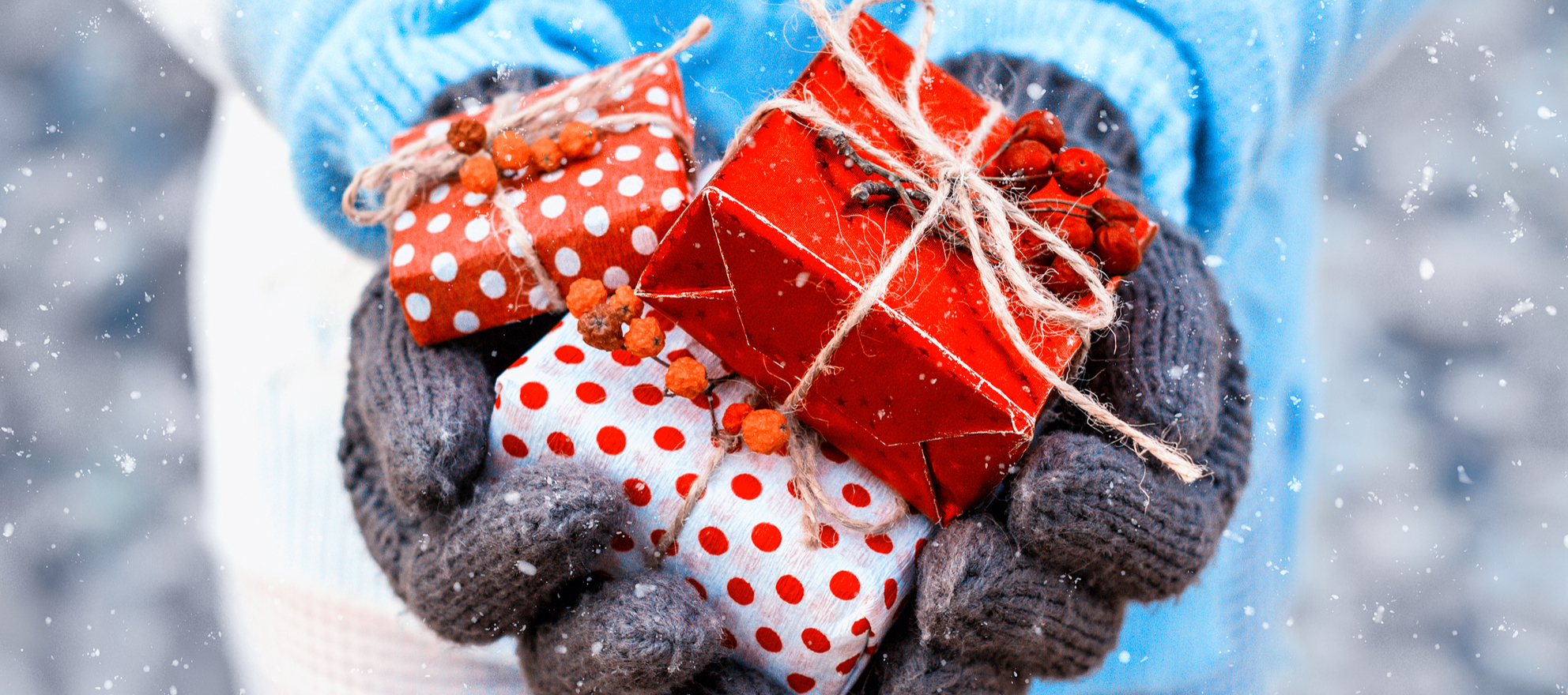 Gloved hands holding out holiday-wrapped gifts