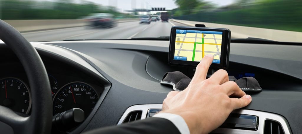 A man's hand navigating GPS while driving