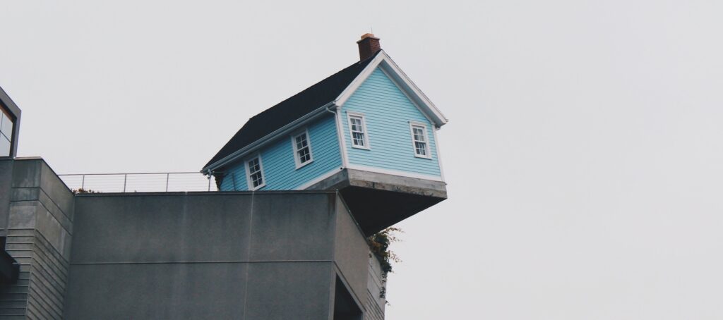 House teetering on the edge of a ledge, balance, tipping
